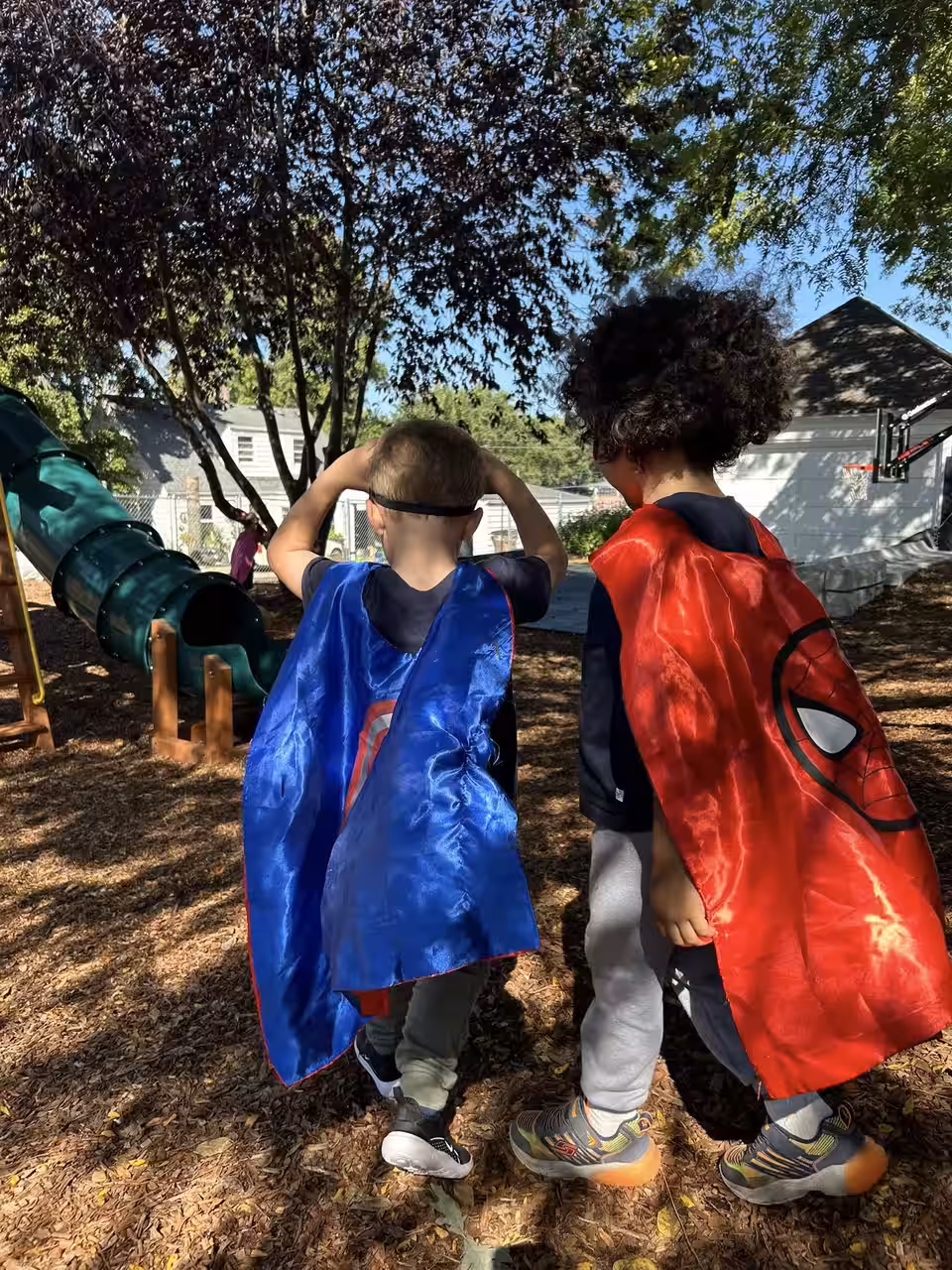 Two children in superhero capes walking through the Main Street School playground