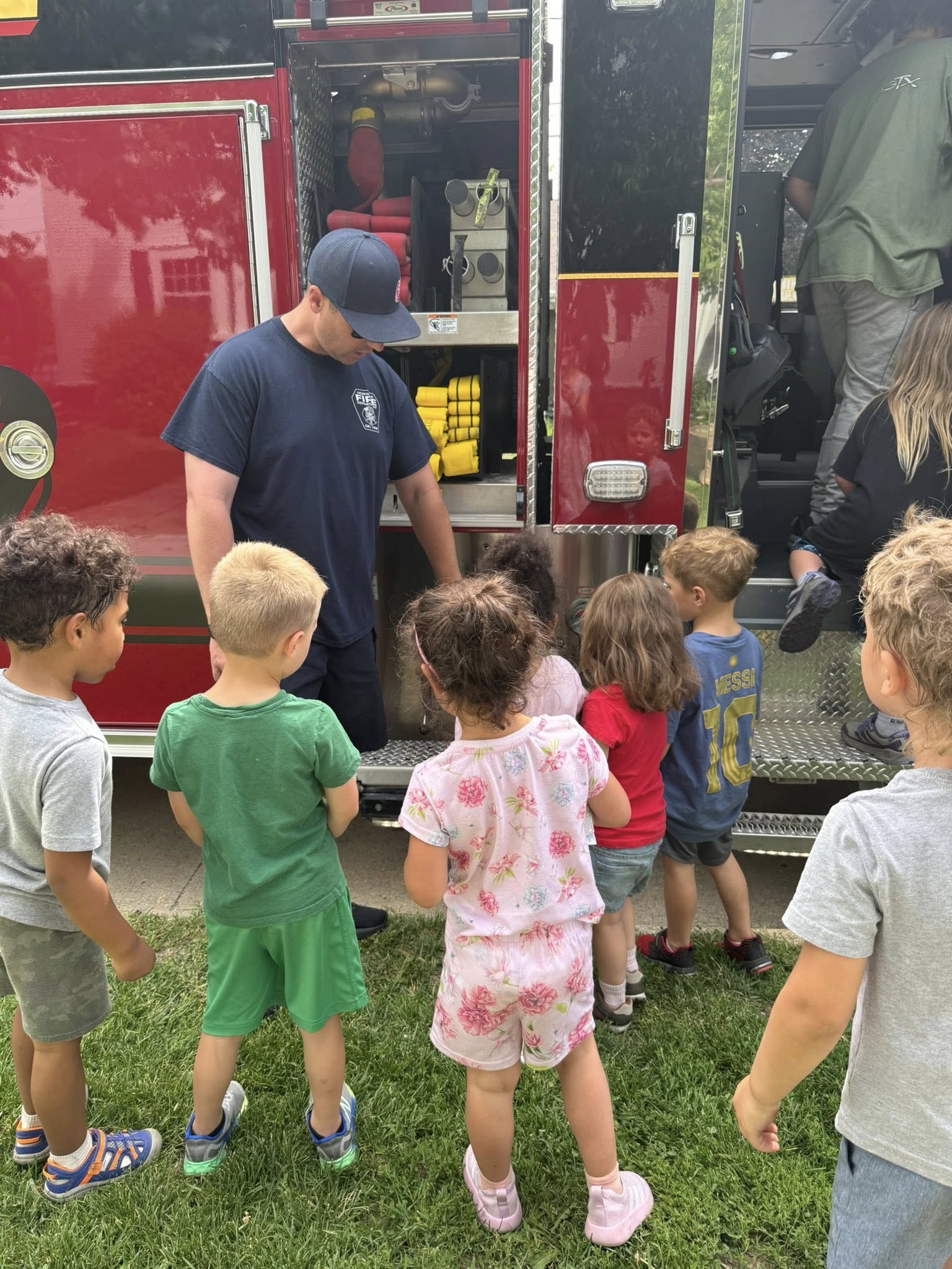 Main Street School students listening to a Norwalk firefighter beside a fire truck