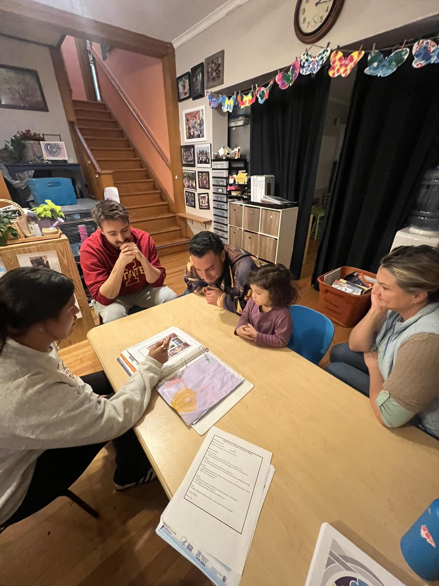 A young Main Street School student sharing classroom work with several attentive adults