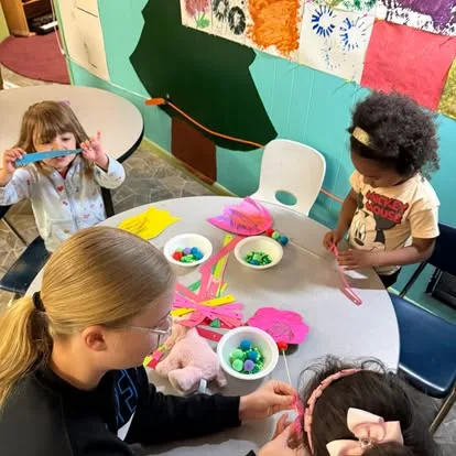 Young Main Street School students creating with colorful materials at a classroom table