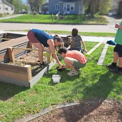 Students and adults building raised garden beds outside Main Street School
