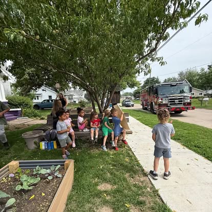 Main Street School students and adults gathered under a tree with a fire truck nearby