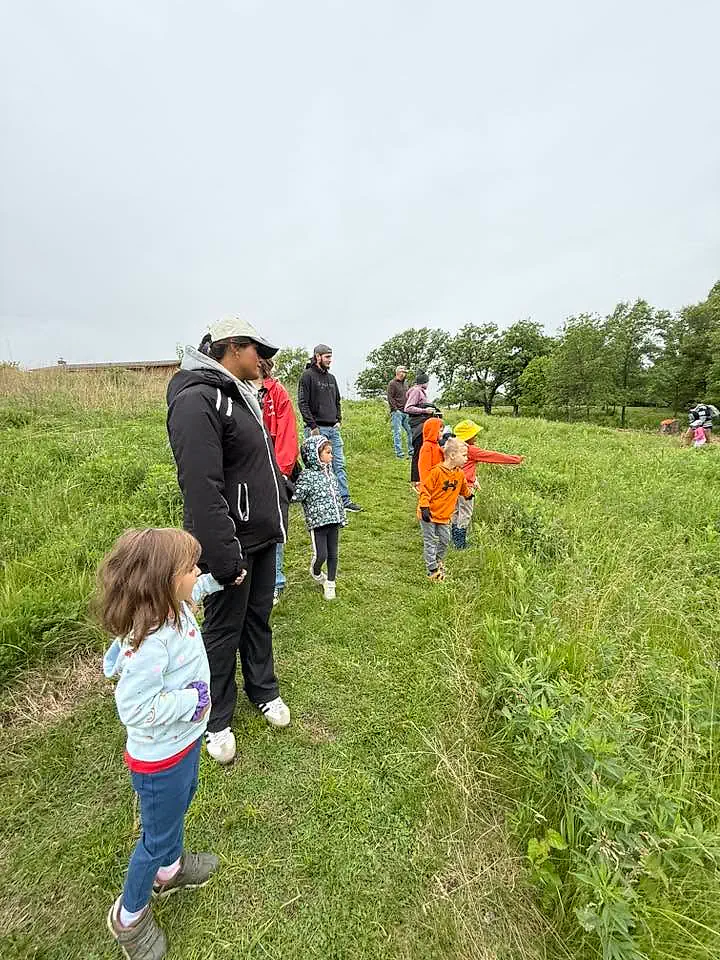 Main Street School students and adults walking through prairie grass on a field trip