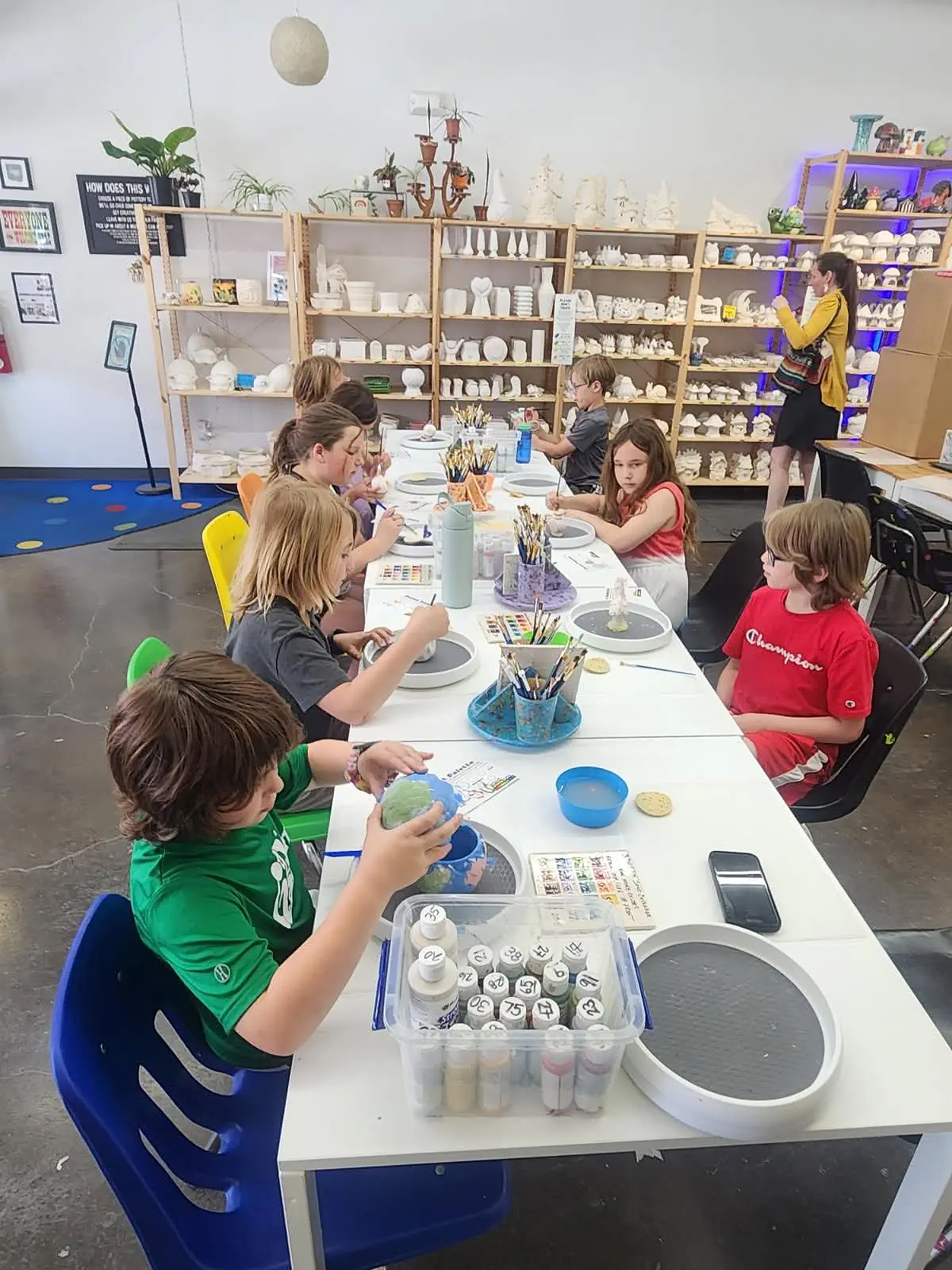 Main Street School students painting and assembling small art materials around a shared table