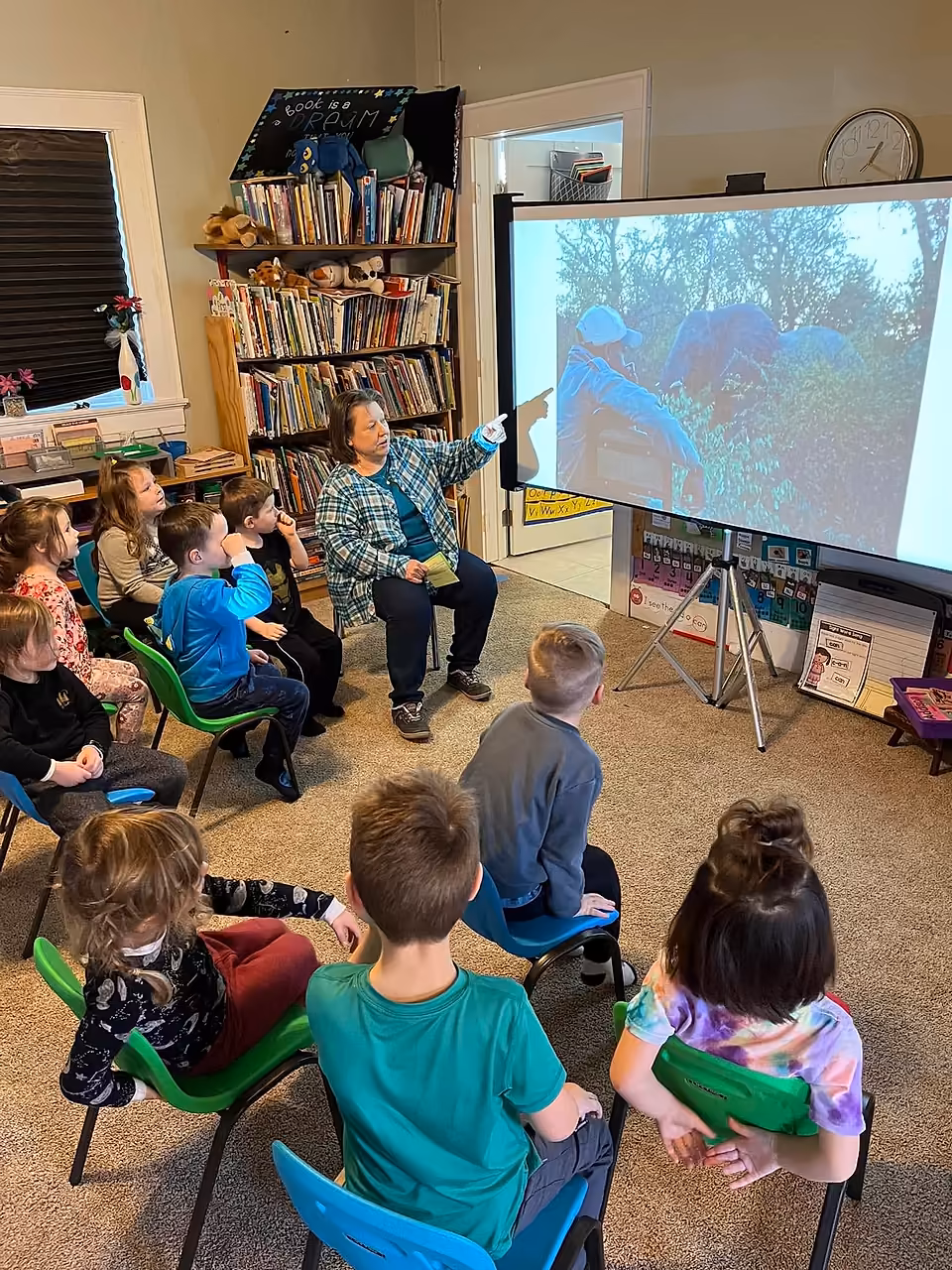 Primary students watching a projected safari scene with an educator in their classroom