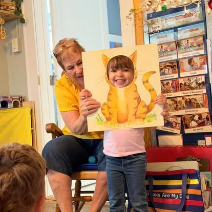 A young Main Street School student sharing an art project with a visiting teacher